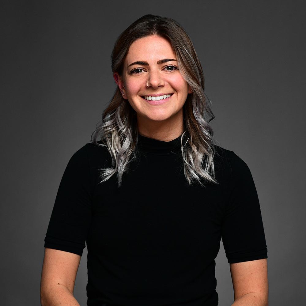 Headshot of Allison Karp. She is wearing a mid -sleeve black shirt. She had hair that goes to over her shoulders and has white-grey lowlights. She is smiling at the camera.  