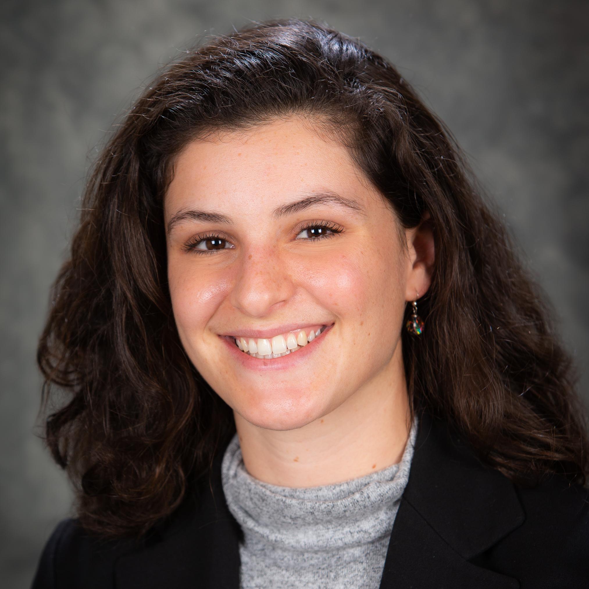 Headshot image of Hannah Gutner. She is wearing black blazer and grey shirt