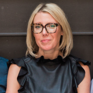 Headshot of Amanda Parsons, short blonde hair, wearing glasses, and a black blouse