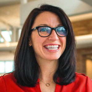 Headshot of Andrea Steffes-Tuttle. She is smiling, wearing glasses and a red shirt.