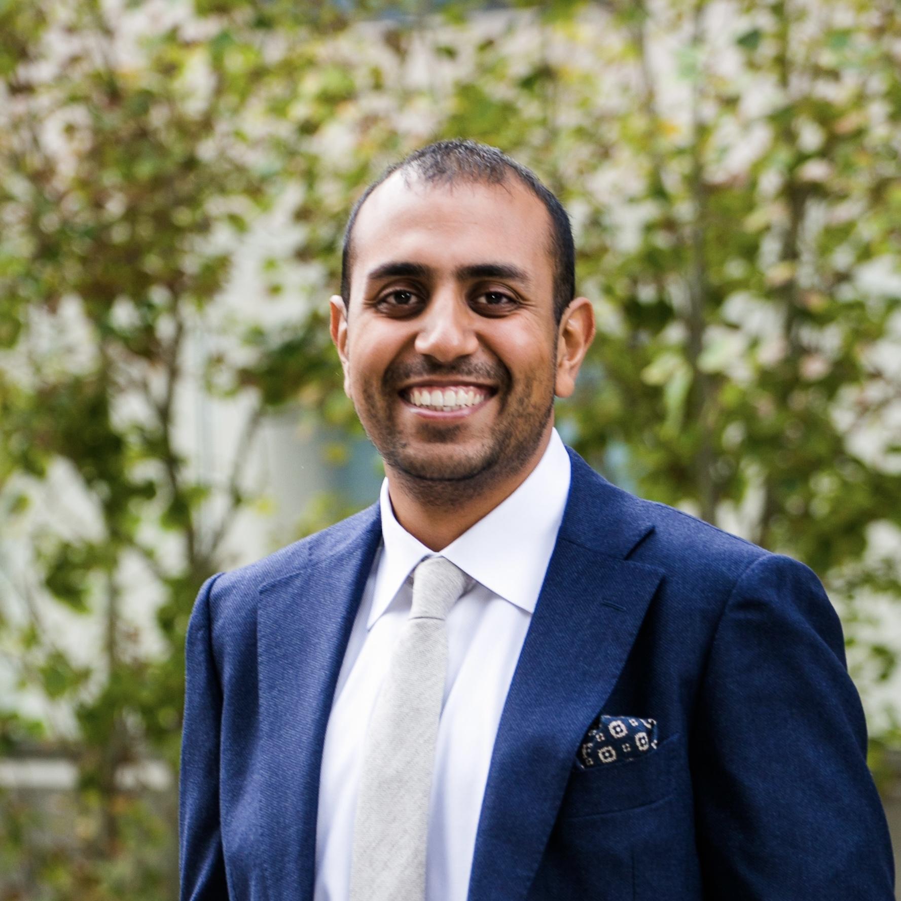Headshot of Vinay Patidar, smiling, navy blue suit jacket, white tie
