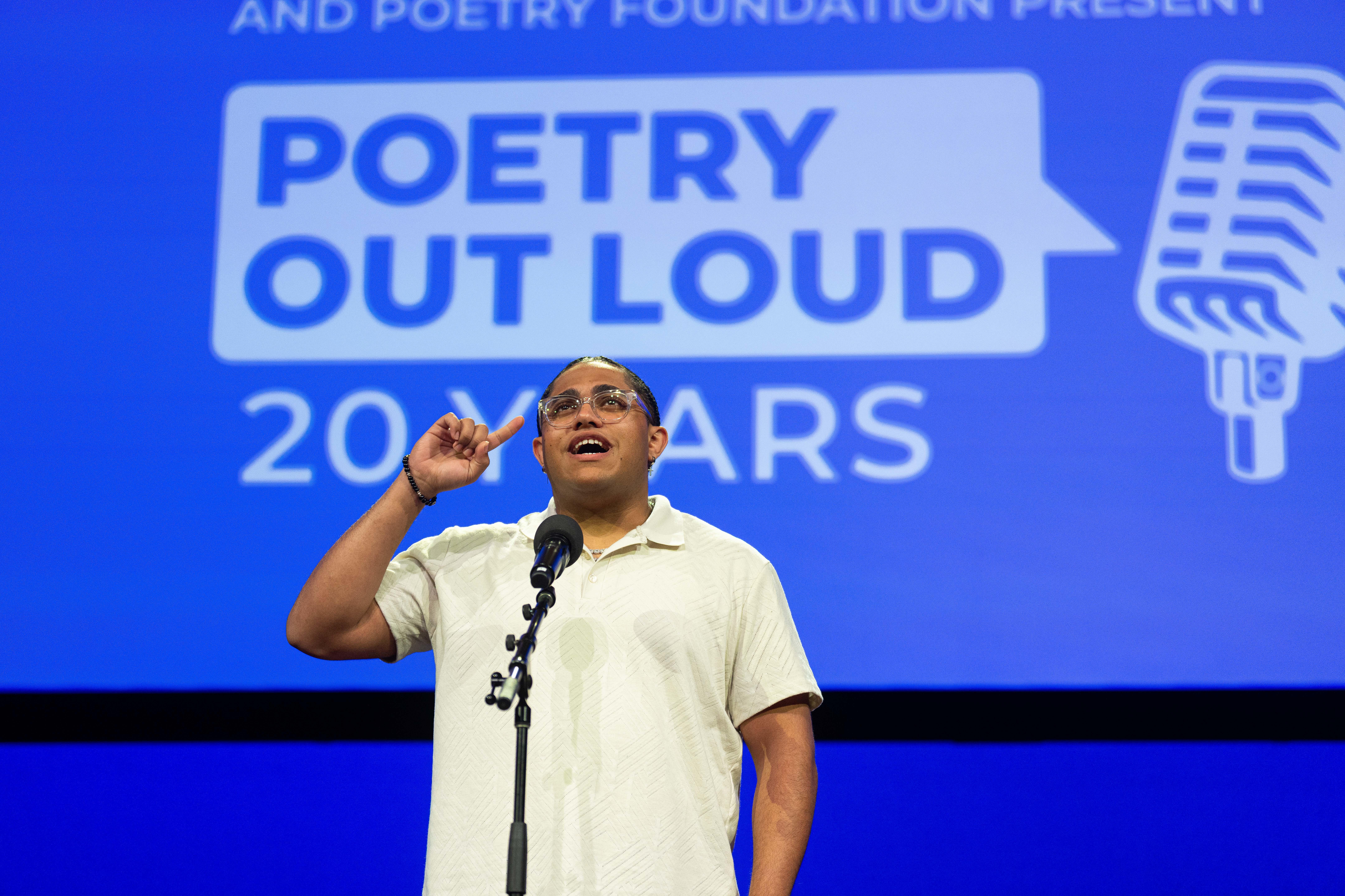 Rize Simmons on stage in front of a large screen that says, "Poetry Out Loud 20 Years".