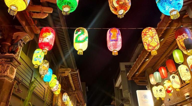 a photo taken at night of multi-colored Chinese lanterns lighting up the pathway