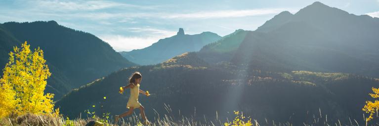Girl on hillside with fall foliage in the background