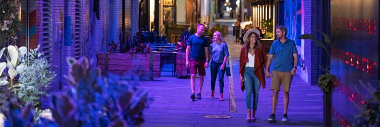 People walking along a lit up Denver walkway.