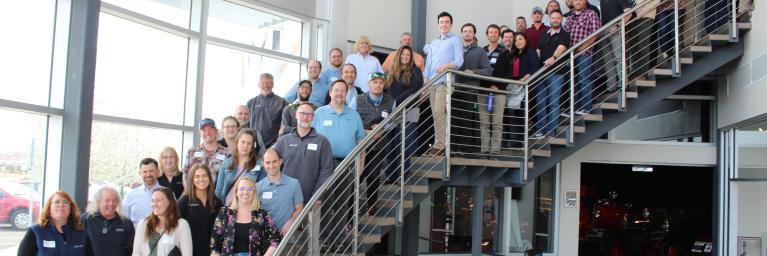 dozens of Baseline engineering employees standing on staircase and smiling 