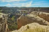 Two hikers approach a cliff's edge looking over a deep valley.